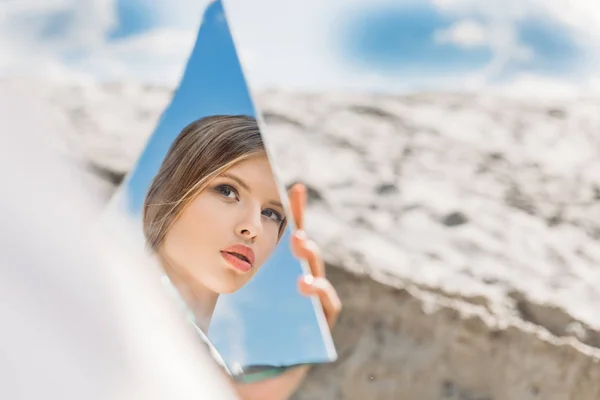 Encantadora menina segurando pedaço de espelho e olhando em seu reflexo — Fotografia de Stock