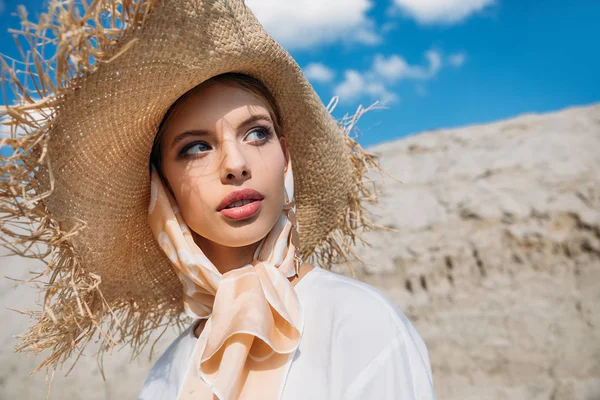 Hermosa mujer joven elegante posando en bufanda de seda de moda y sombrero de paja - foto de stock