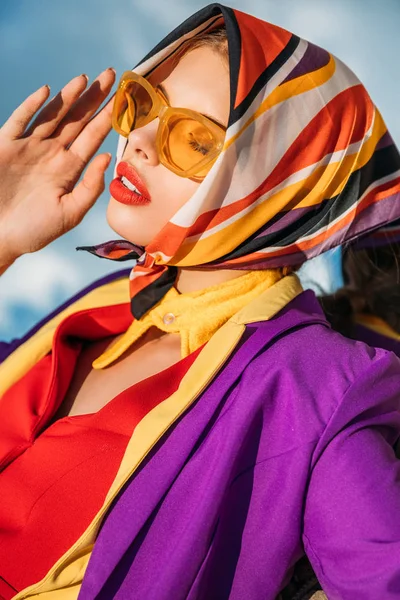 Belle dame posant en lunettes de soleil jaunes et écharpe colorée en soie — Photo de stock