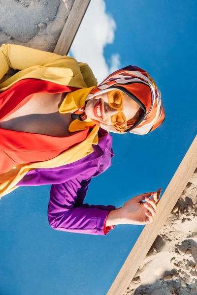 Draufsicht auf elegant lächelnde Frau, die auf Spiegel im Sand liegt — Stockfoto