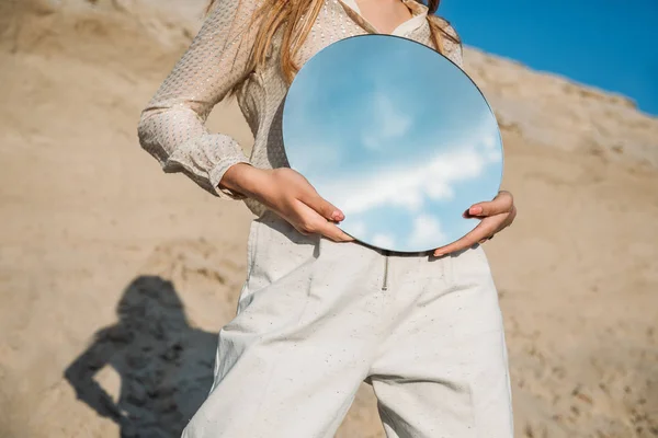 Vista ritagliata di elegante ragazza tenendo specchio con riflesso del cielo blu con nuvole — Foto stock