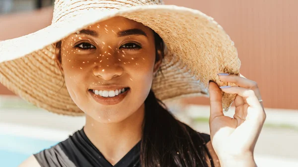 Lächelnde junge asiatische Frau in Badeanzug und Strohhut — Stockfoto