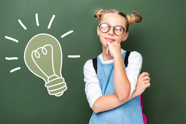 Scuola pensieroso in occhiali guardando verso l'alto vicino lavagna con segno lampadina — Foto stock