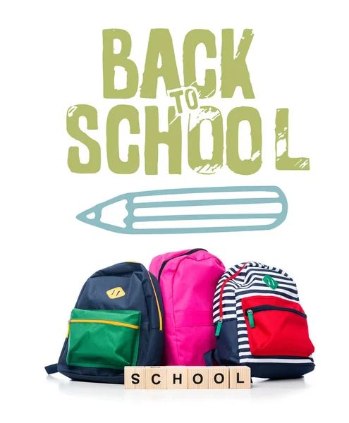 Tres bolsos escolares de colores y cubos de madera con escuela de palabras aisladas en blanco, con lápiz y letras de 