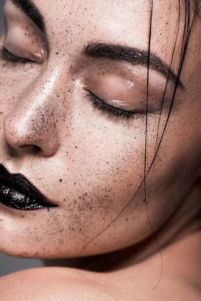 Primer plano retrato de mujer joven con labios negros y pecas en la cara, aislado en gris - foto de stock