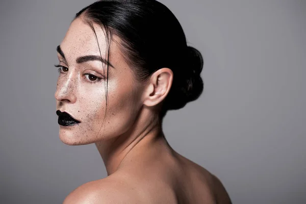 Portrait of beautiful girl with black lips and freckles posnig for fashion shoot, isolated on grey — Stock Photo