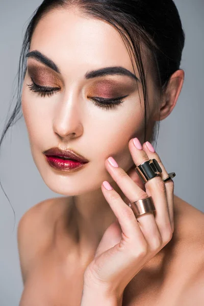 Retrato de hermosa chica con los ojos cerrados posando con anillos de oro en la mano, aislado en gris - foto de stock