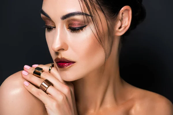 Retrato de chica elegante con maquillaje y anillos de oro, aislado en negro - foto de stock