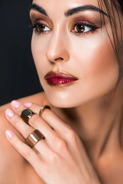 Mujer de moda con maquillaje y anillos de oro en la mano, aislado en negro - foto de stock
