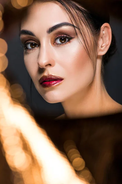 Elegante modello alla moda con trucco in posa su nero con bokeh dorato — Foto stock