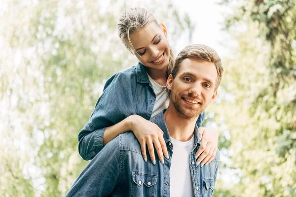 Belle jeune femme piggybackking sur son copain au parc — Photo de stock