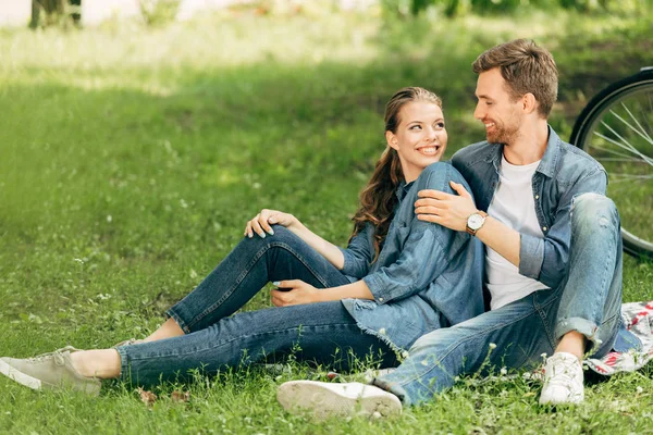 Feliz joven pareja sentado en la hierba en el parque juntos — Stock Photo
