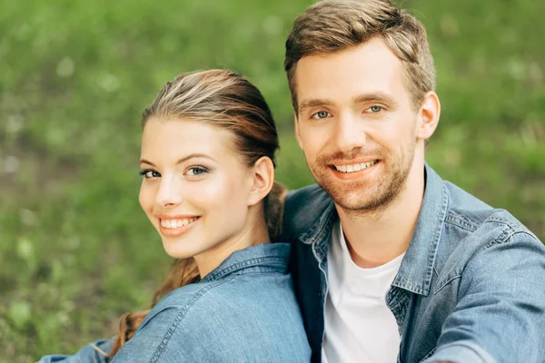 Nahaufnahme Porträt eines glücklichen jungen Paares, das Zeit miteinander im Park verbringt und in die Kamera blickt — Stockfoto