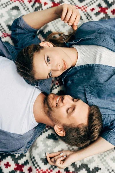 Vista superior de belo jovem casal deitado em pano estampado e flertando — Fotografia de Stock