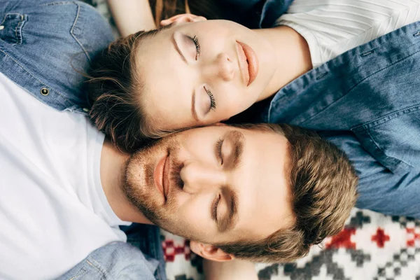 Top view of attractive young couple lying on patterned cloth with closed eyes — Stock Photo