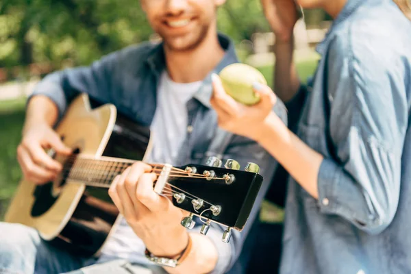 Ritagliato colpo di uomo suonare la chitarra per la fidanzata al parco — Stock Photo