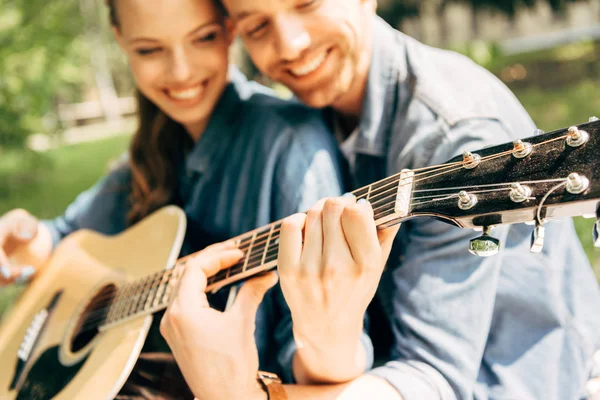 Primo piano colpo di giovane donna felice con fidanzato suonare la chitarra insieme al parco — Stock Photo