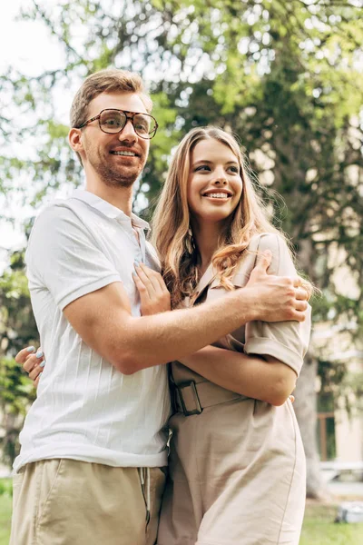 Blick von unten auf schönes junges Paar, das sich im Park umarmt — Stockfoto
