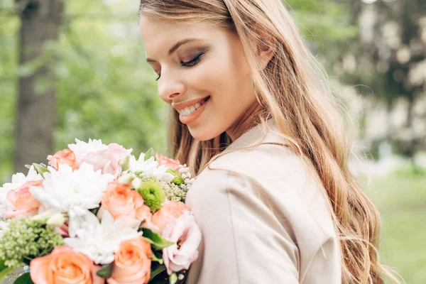 Retrato de cerca de la joven mujer feliz mirando ramo de flores - foto de stock