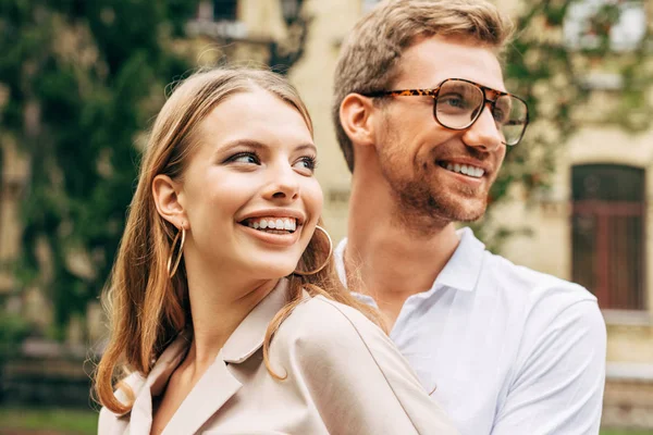 Portrait en gros plan de jeune couple souriant dans des vêtements élégants détournant les yeux — Photo de stock