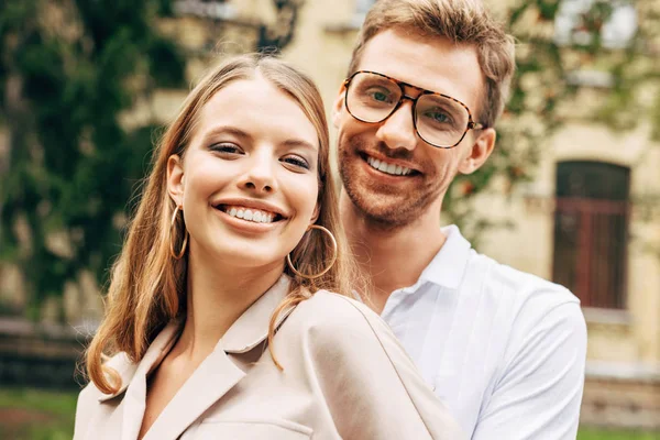 Primer plano retrato de sonriente pareja joven en ropa elegante mirando a la cámara - foto de stock