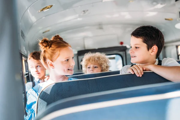 Grupo de pequeños alumnos felices montando en el autobús escolar - foto de stock