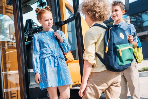 Группа школьников, стоящих возле школьного автобуса и разговаривающих — стоковое фото