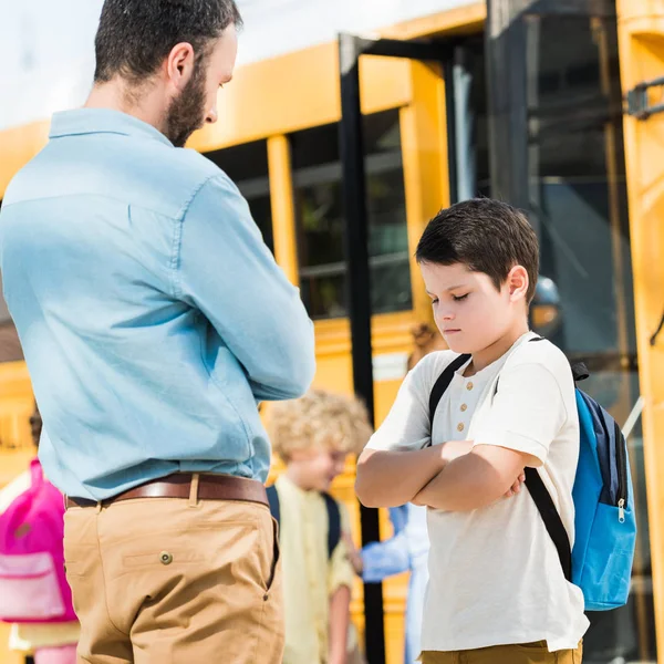 Сердитий батько проповідує свого депресивного сина перед шкільним автобусом — стокове фото