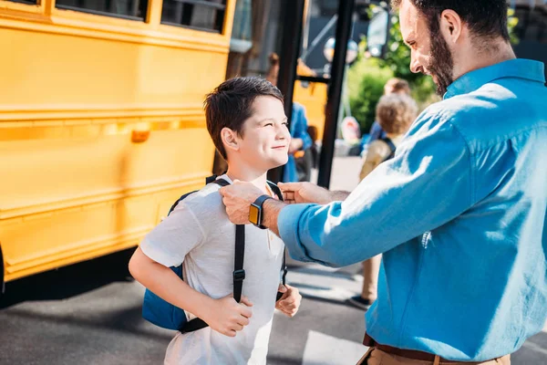 Щасливий батько стоїть зі своїм сином перед шкільним автобусом — стокове фото