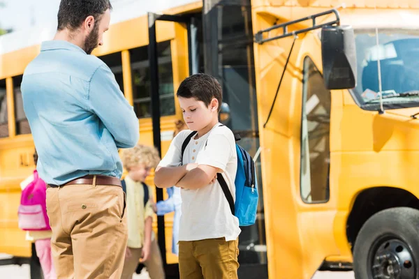 Father preaching his son in front of school bus — Stock Photo