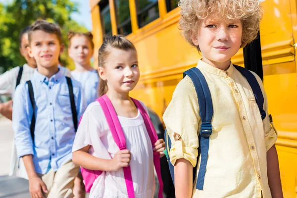 Groupe de camarades de classe adorables près du bus scolaire — Photo de stock