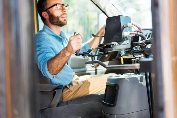 Handsome school bus driver losing door with lever and looking at rear mirror — Stock Photo