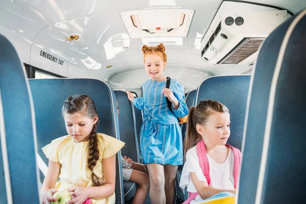 Adorables pequeños alumnos montados en el autobús escolar durante la excursión - foto de stock