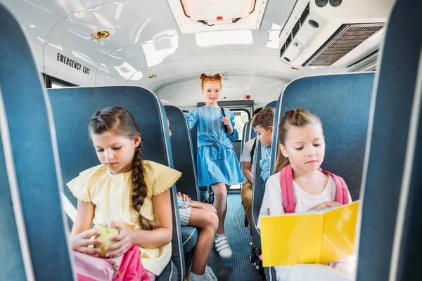 Entzückende kleine Schulkinder, die während eines Ausflugs im Schulbus fahren — Stockfoto
