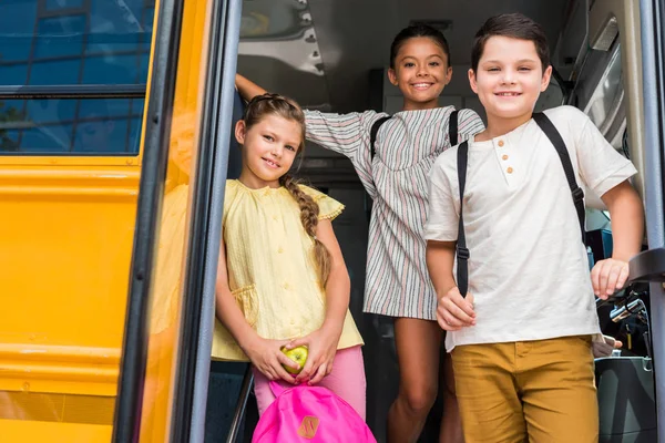 Group of adorable pupils standing at school bus — Stock Photo