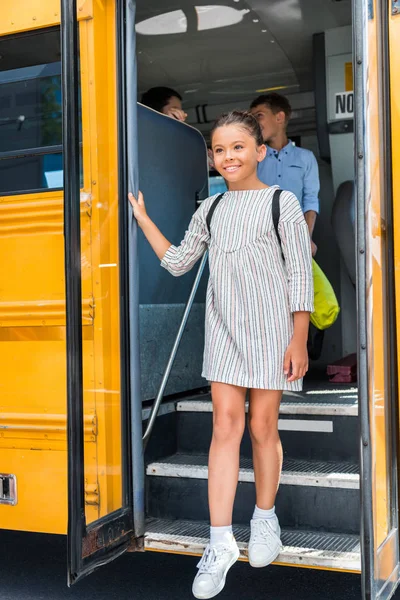 Eruditos felices saliendo del autobús escolar - foto de stock