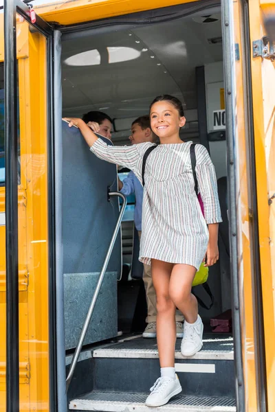 Hermosa colegiala saliendo de autobús escolar - foto de stock
