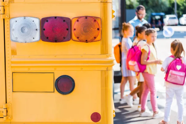 Задние фонари школьного автобуса с размытыми на заднем плане учениками — стоковое фото