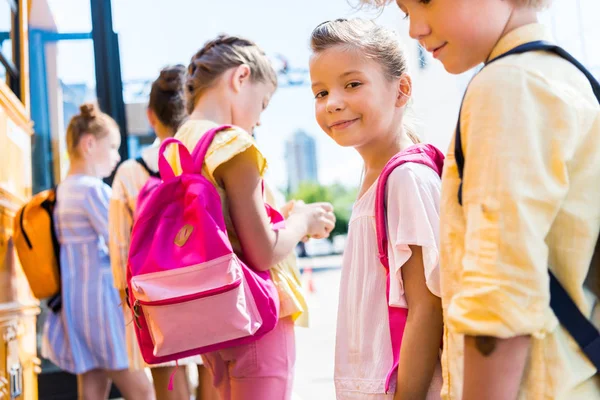 Gros plan d'adorables écoliers debout près d'un autobus scolaire — Photo de stock