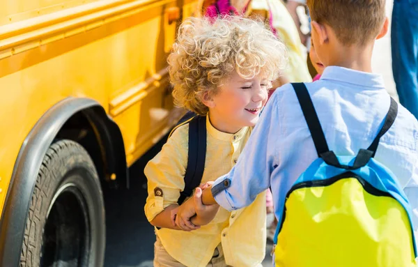 Rear view of adorable scholars playing near school bus — Stock Photo