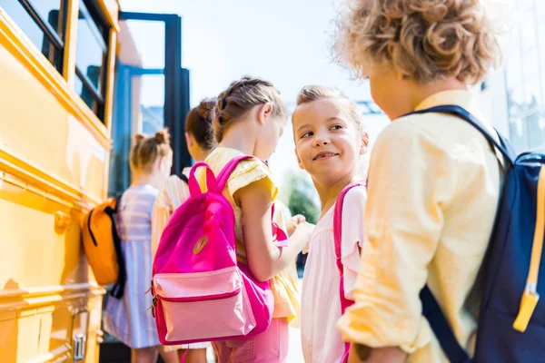 Primo piano di gruppo di adorabili scolari in piedi vicino allo scuolabus — Foto stock