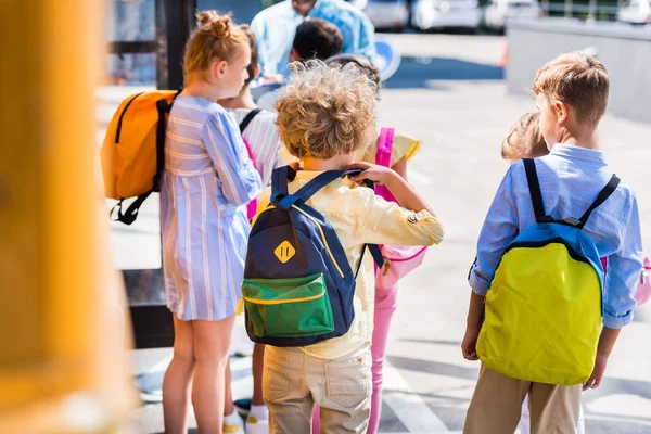 Rückansicht einer Schülergruppe in der Nähe eines Schulbusses — Stockfoto