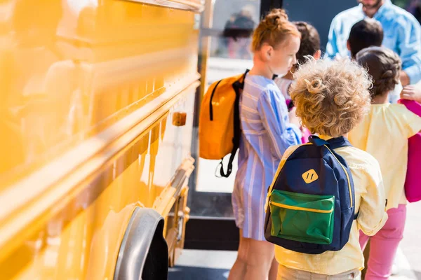 Rückansicht einer Schülergruppe in der Nähe eines Schulbusses — Stockfoto