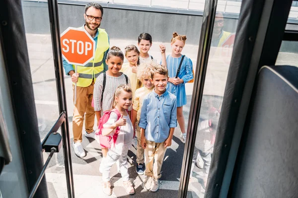Вид зі шкільного автобуса на групу щасливих вчених з охоронцем, який дивиться на камеру — стокове фото