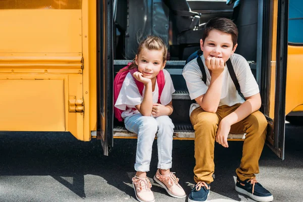 Adorable little scholars sitting on stairs of school bus — Stock Photo