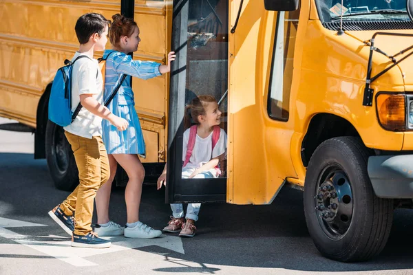 Estudiosos relaxando perto de ônibus escolar no estacionamento — Fotografia de Stock