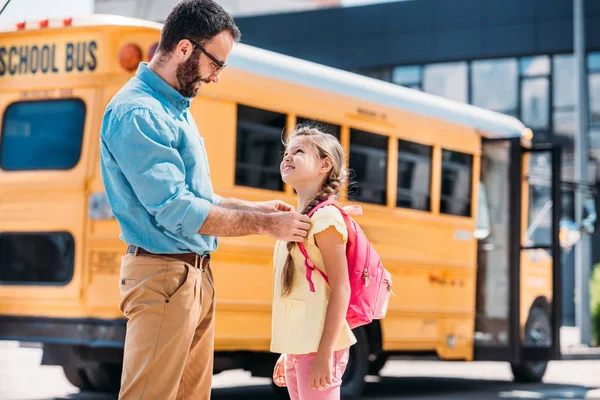 Батько стоїть зі своєю дочкою перед шкільним автобусом — стокове фото