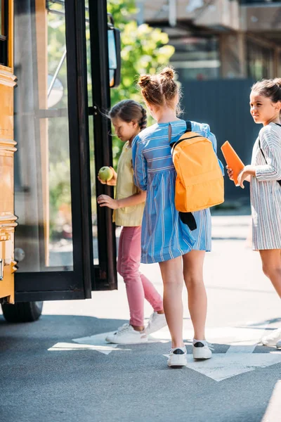 Groupe de petites écolières écolières entrant dans le bus scolaire — Photo de stock