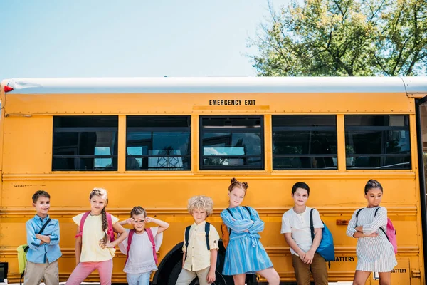 Grupo de estudiosos felizes posando na frente do ônibus escolar — Fotografia de Stock