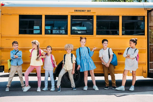 Grupo de alunos felizes posando na frente do ônibus escolar — Fotografia de Stock